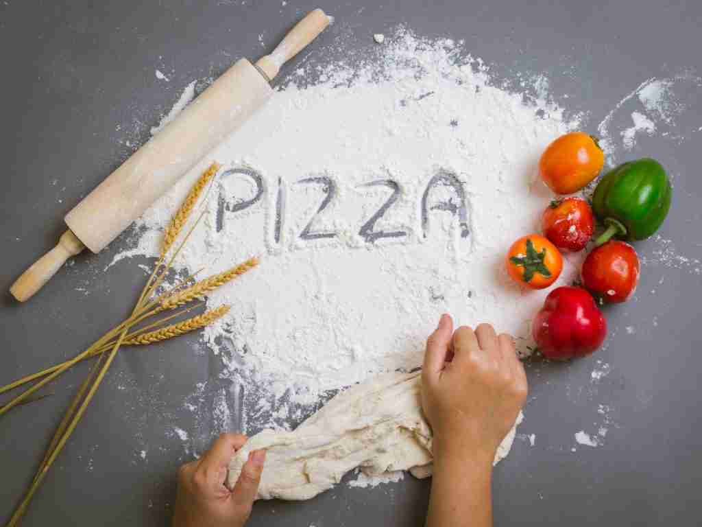 flour on the table and woman kneading a dough for pizza