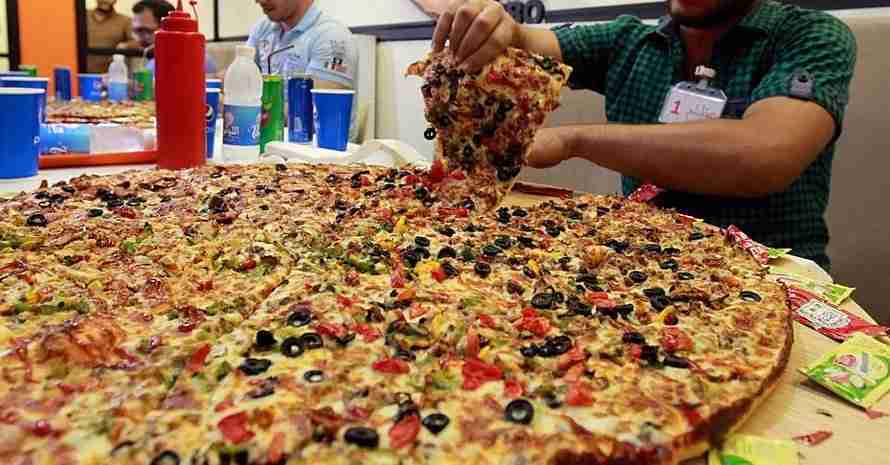 Man takes a slice of large pizza